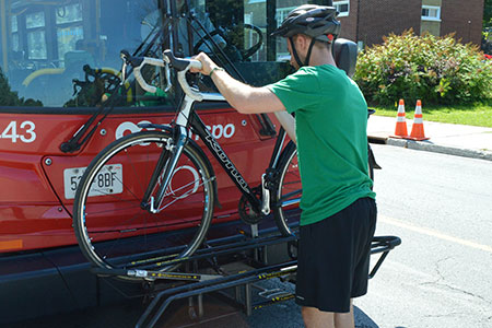 A man places his bike on the rack on the front of a bus