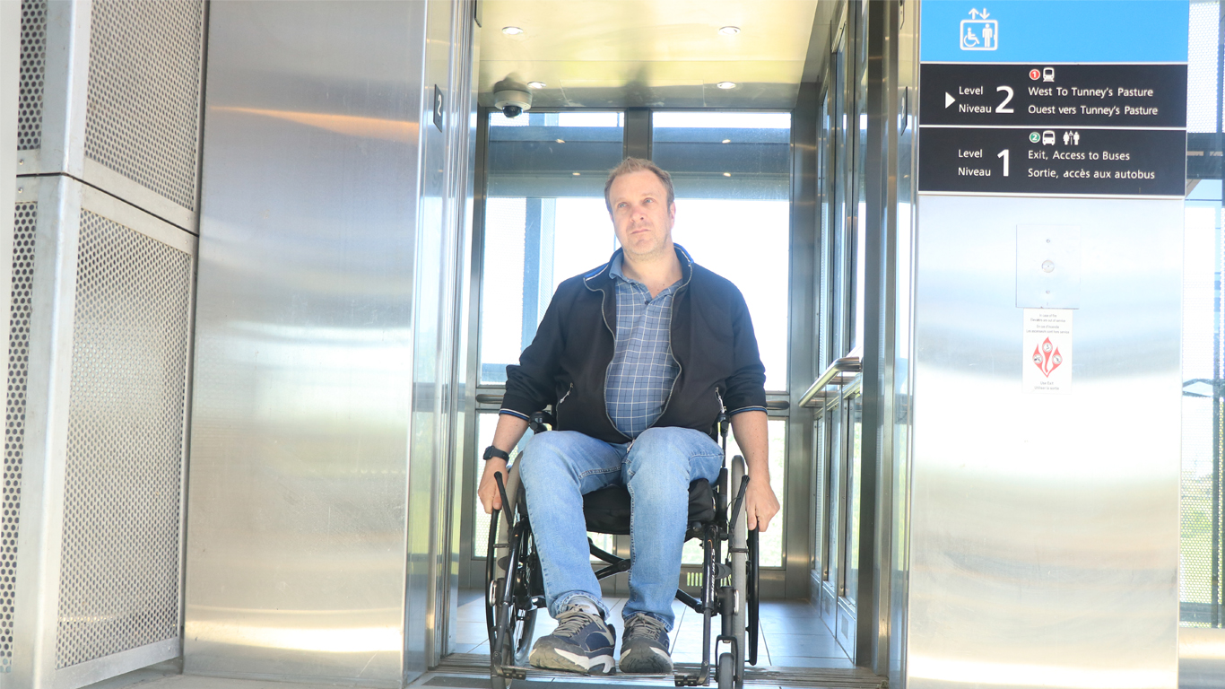 Usager en fauteuil roulant prenant l'ascenseur à la station O-Train