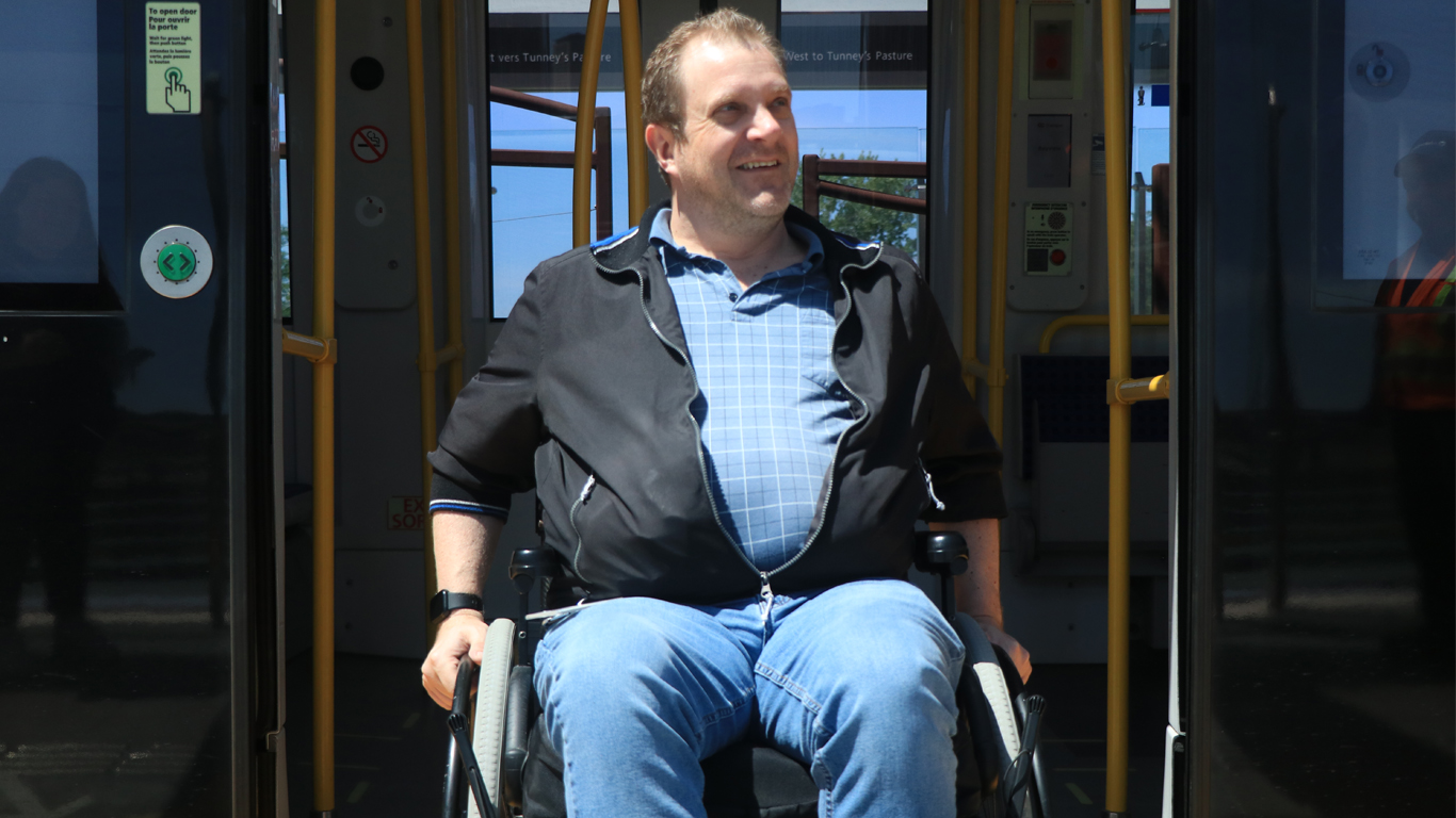 Un passager en fauteuil roulant descendant de l'O-train