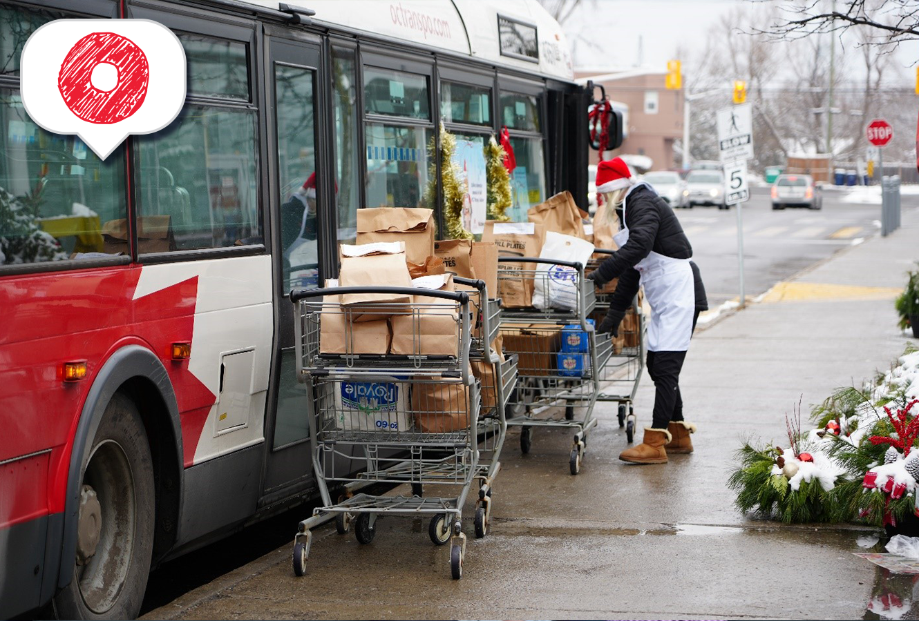 Une bénévole portant un chapeau du père Noël charge des dons alimentaires dans un autobus